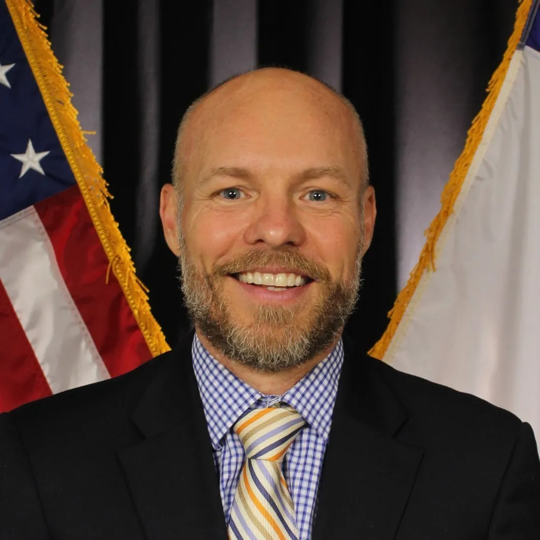 William Wells smiles to the camera with a neutral background